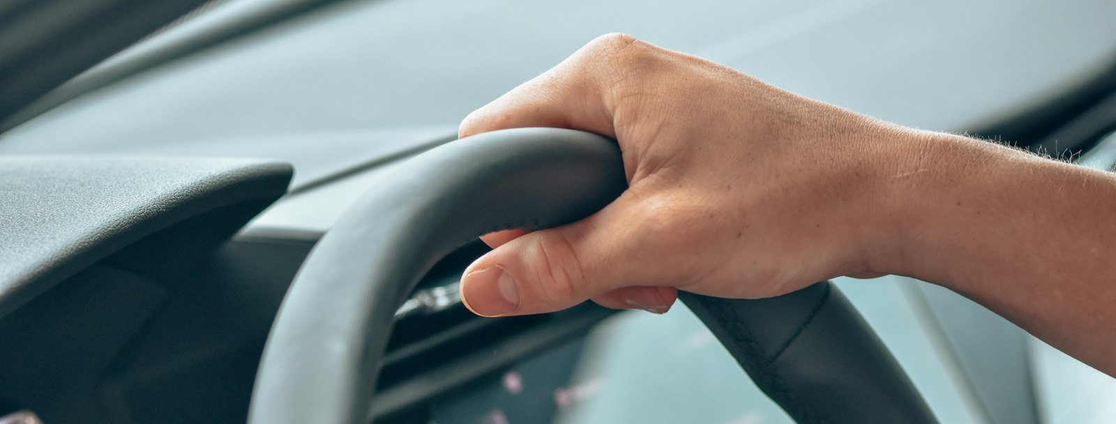 Driver's hand resting on the steering wheel of a modern car