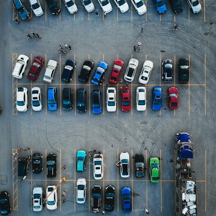 Aerial view of a large parking lot with rows of parked cars