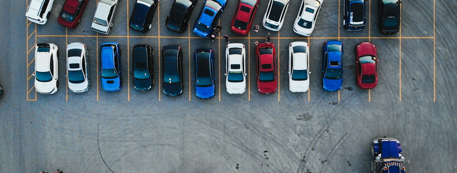 Aerial view of a large parking lot with rows of parked cars