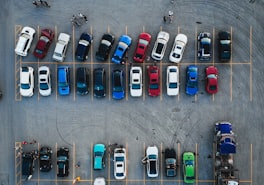 Aerial view of a large parking lot with rows of parked cars